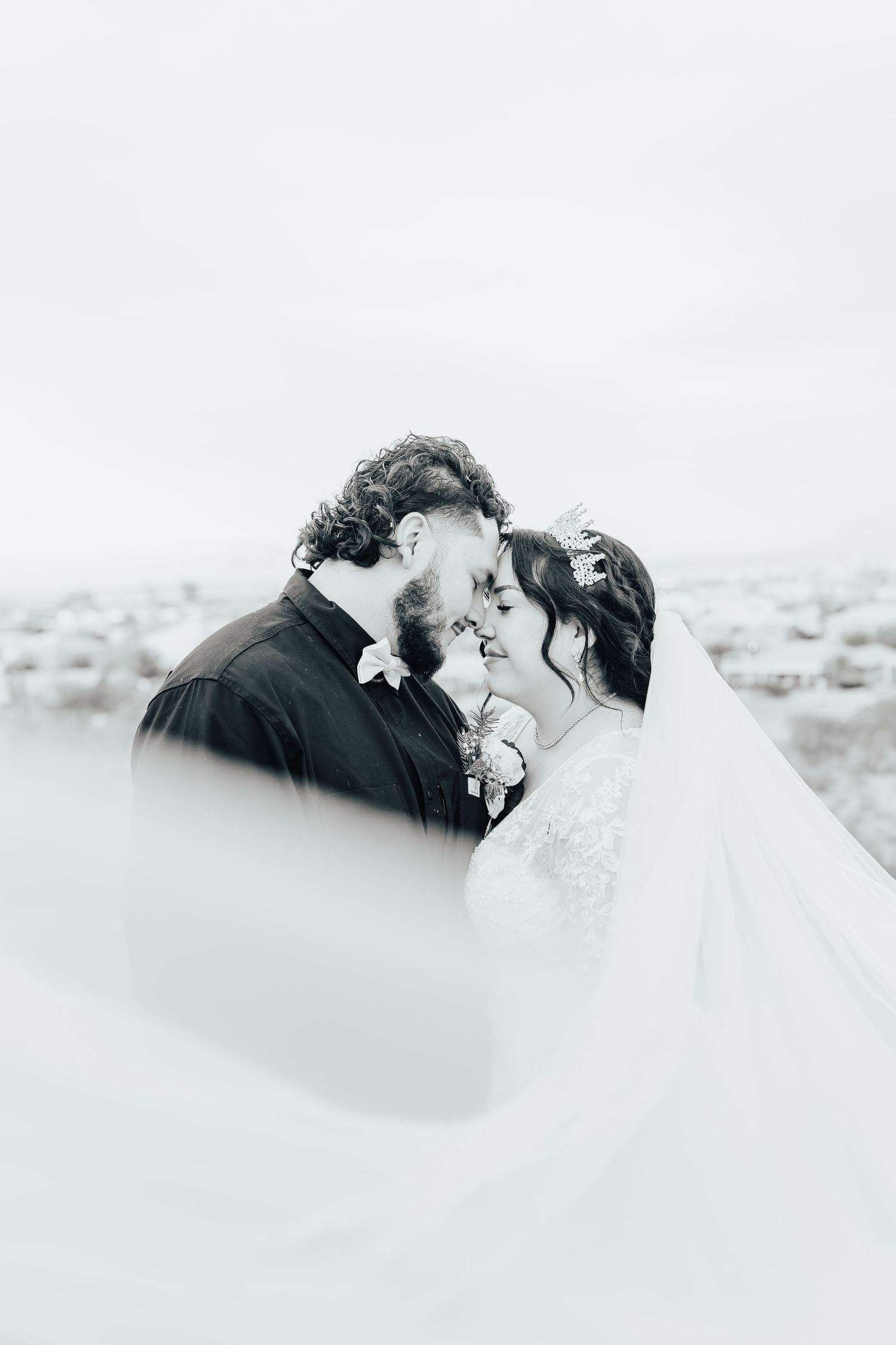Black and white romantic wedding portrait of a couple sharing an intimate moment in their wedding attire.
