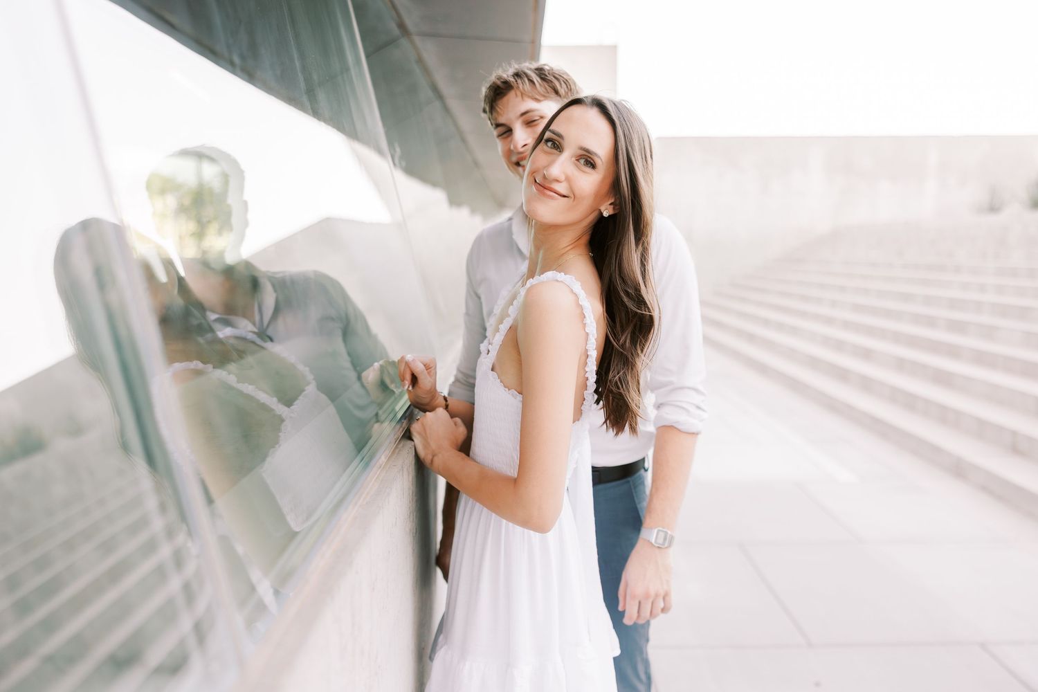 Couple sharing tender moments against modern white architectural backdrop.