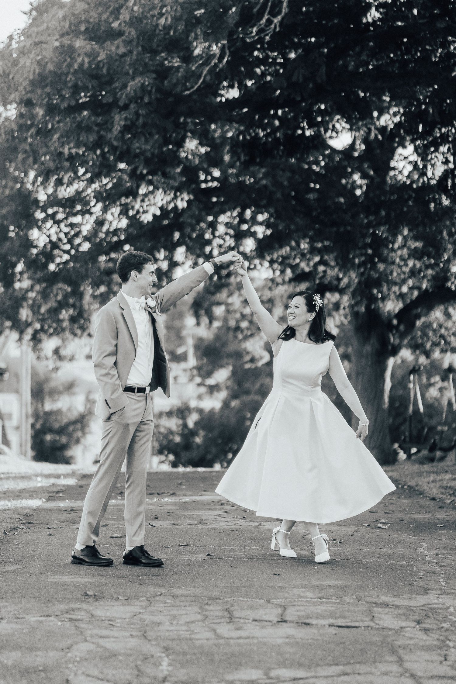 Black and white photo of wedding couple walking together on stone path.