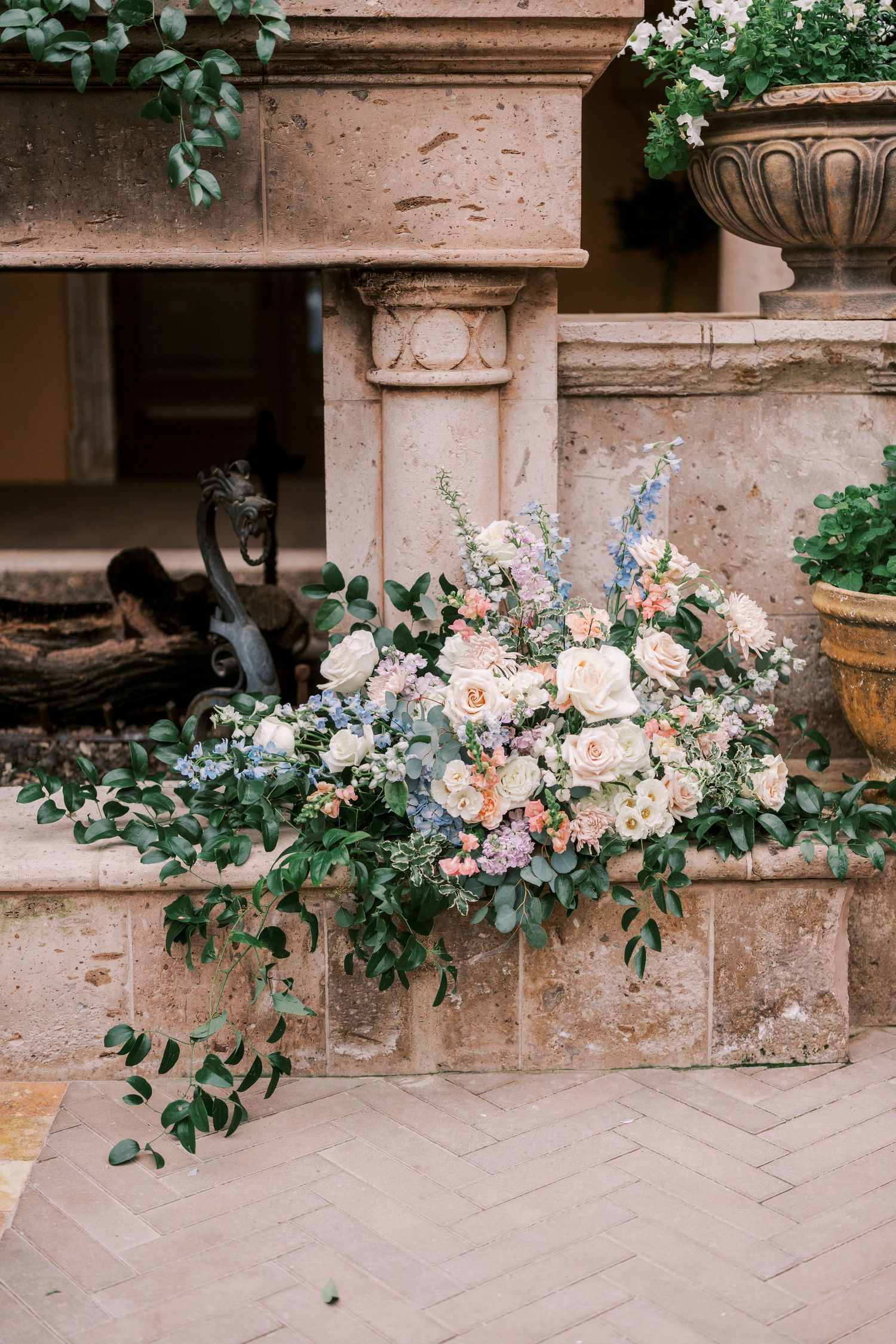 Elegant floral arrangement with pink and white blooms cascading along stone architectural details.