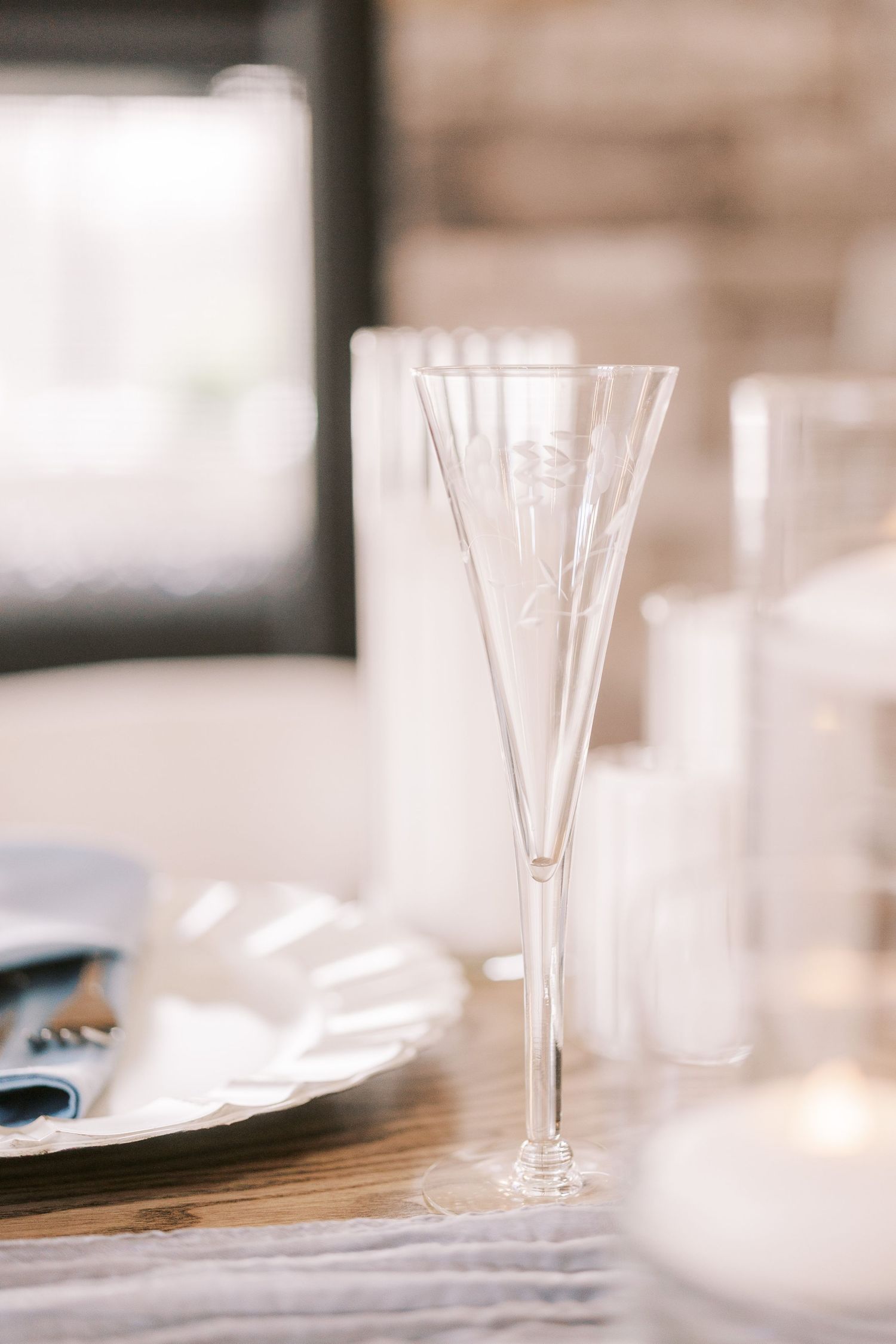 Empty champagne flutes on a rustic wooden table with soft focus and natural lighting create an elegant dining setting.