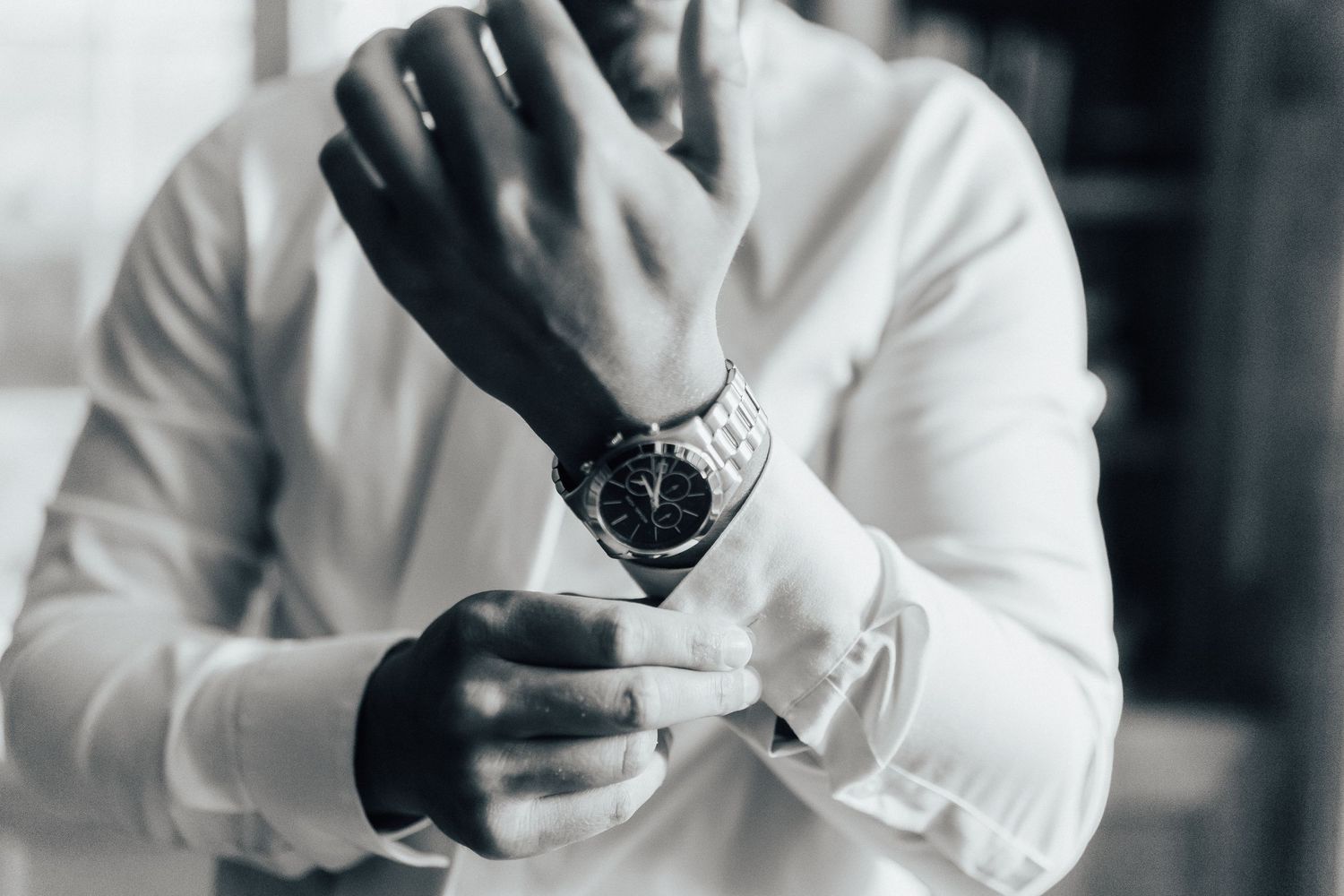 Black and white image showing hands with elegant cufflinks and formal attire.