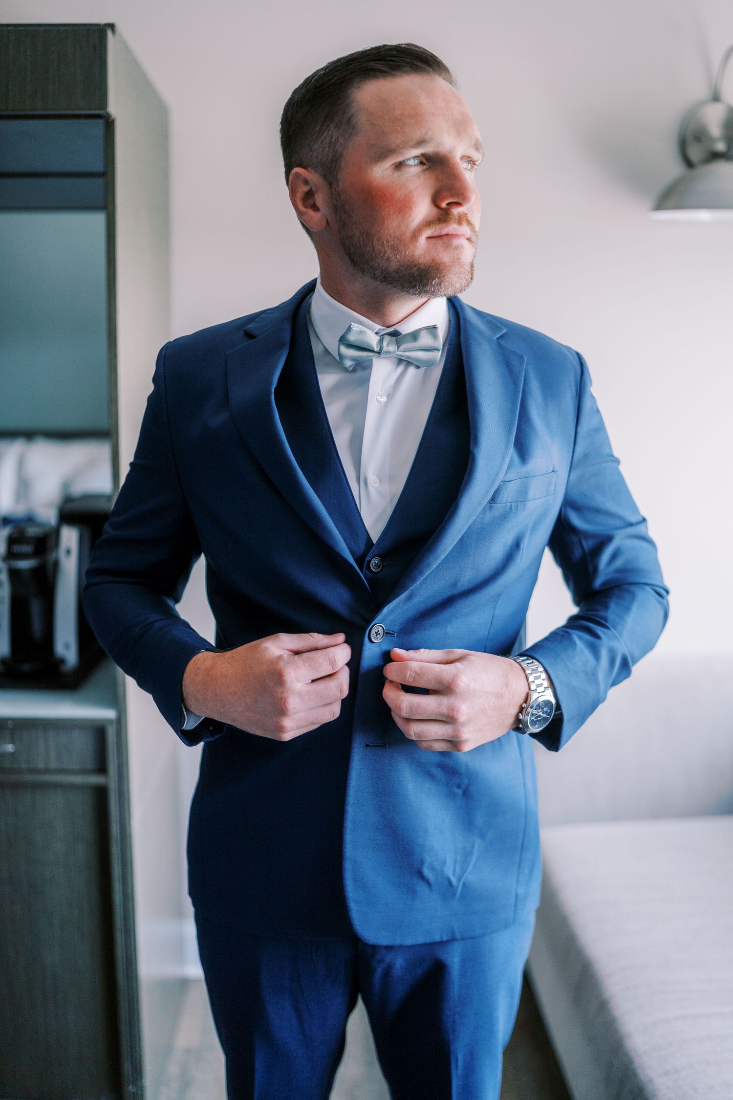 A series of photos showing a person in a blue suit adjusting their jacket and getting dressed in formal attire.