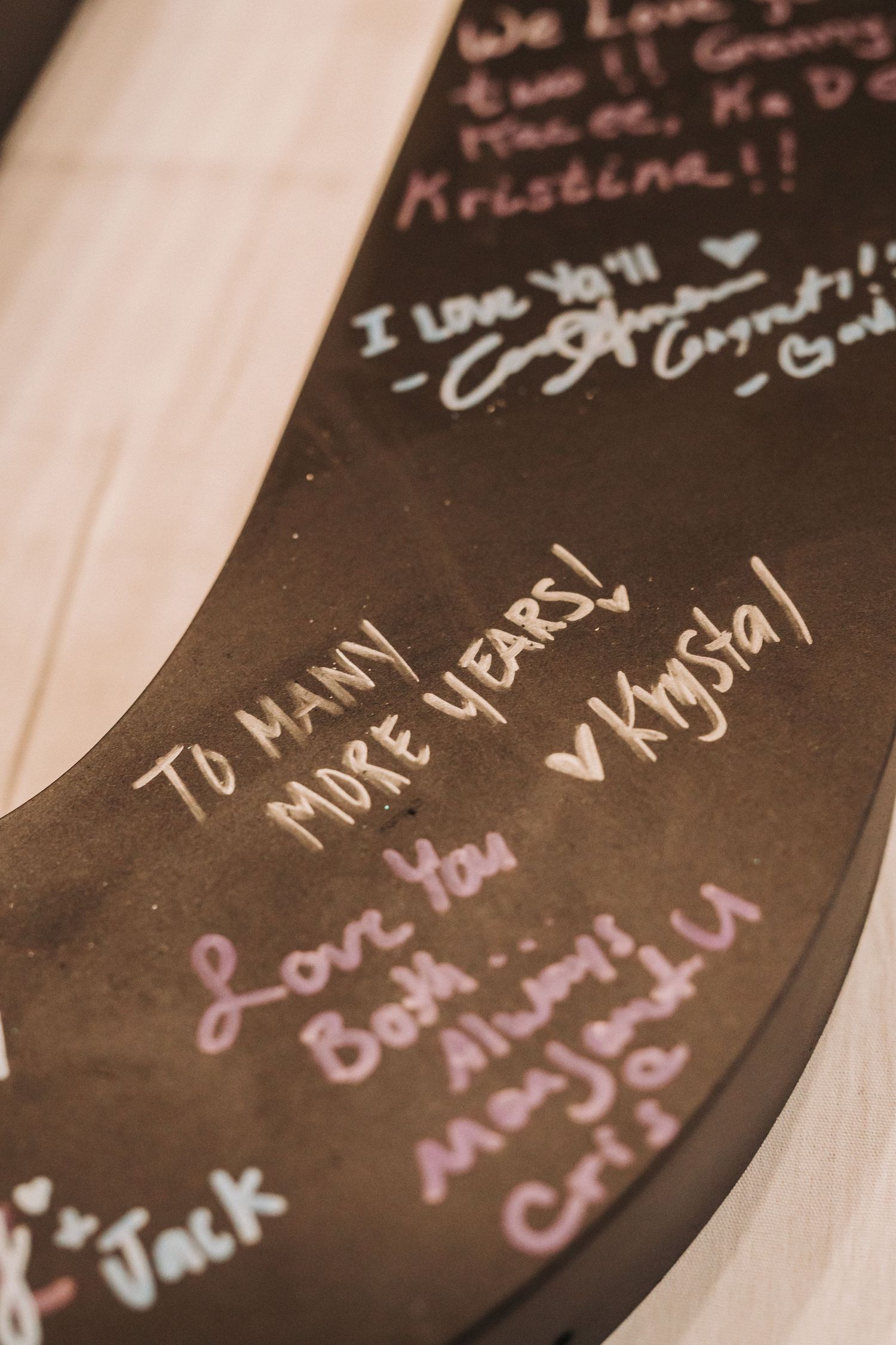 Handwritten messages of love and well wishes written in various colors on a dark surface.