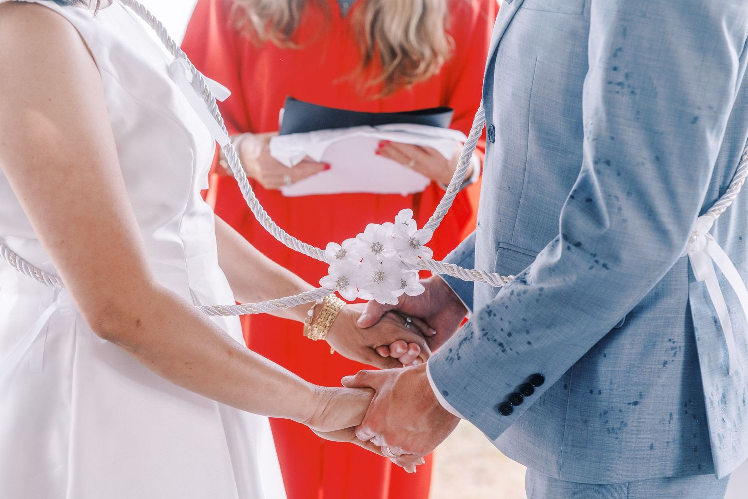 Close-up shot of hands exchanging wedding rings during an outdoor ceremony.