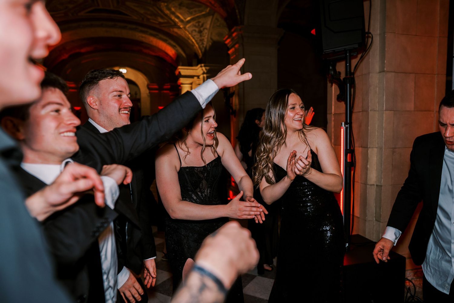 Partygoers dancing and socializing at an elegant indoor venue with stone columns.