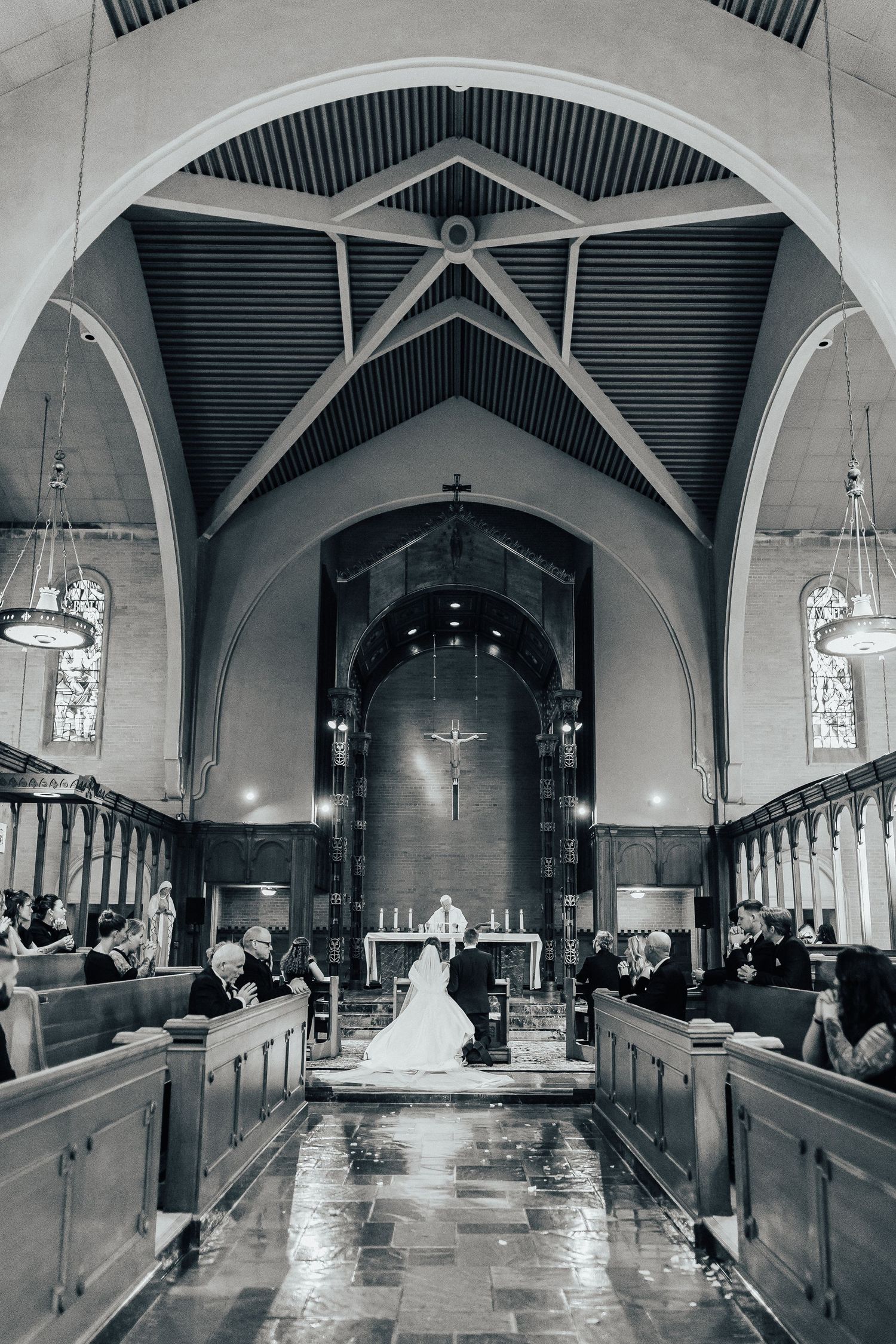 Black and white photograph of a church interior with Gothic arches and wooden pews.