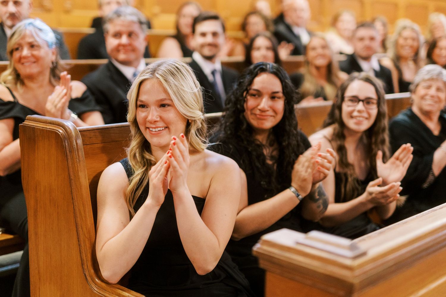 Wedding guests react with joy and excitement during an emotional moment in a church ceremony.