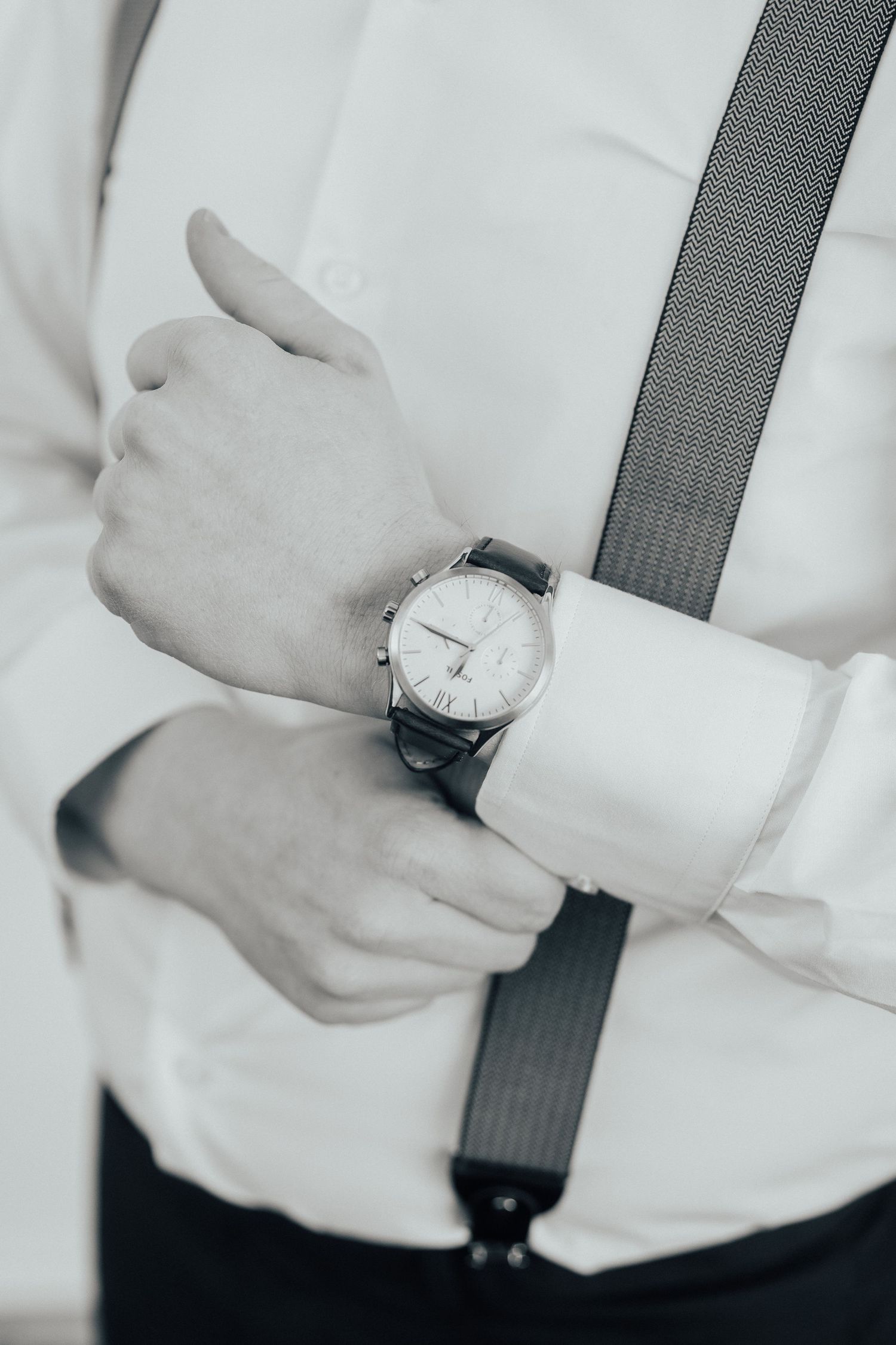 A sequence of hands adjusting and rolling up white shirt sleeves against a dark background.