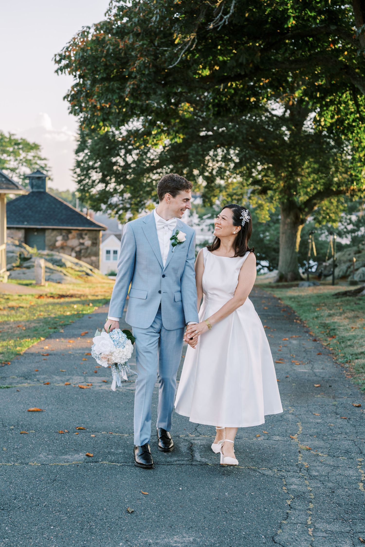 A romantic photo sequence of a couple walking together on a tree-lined path in wedding attire.