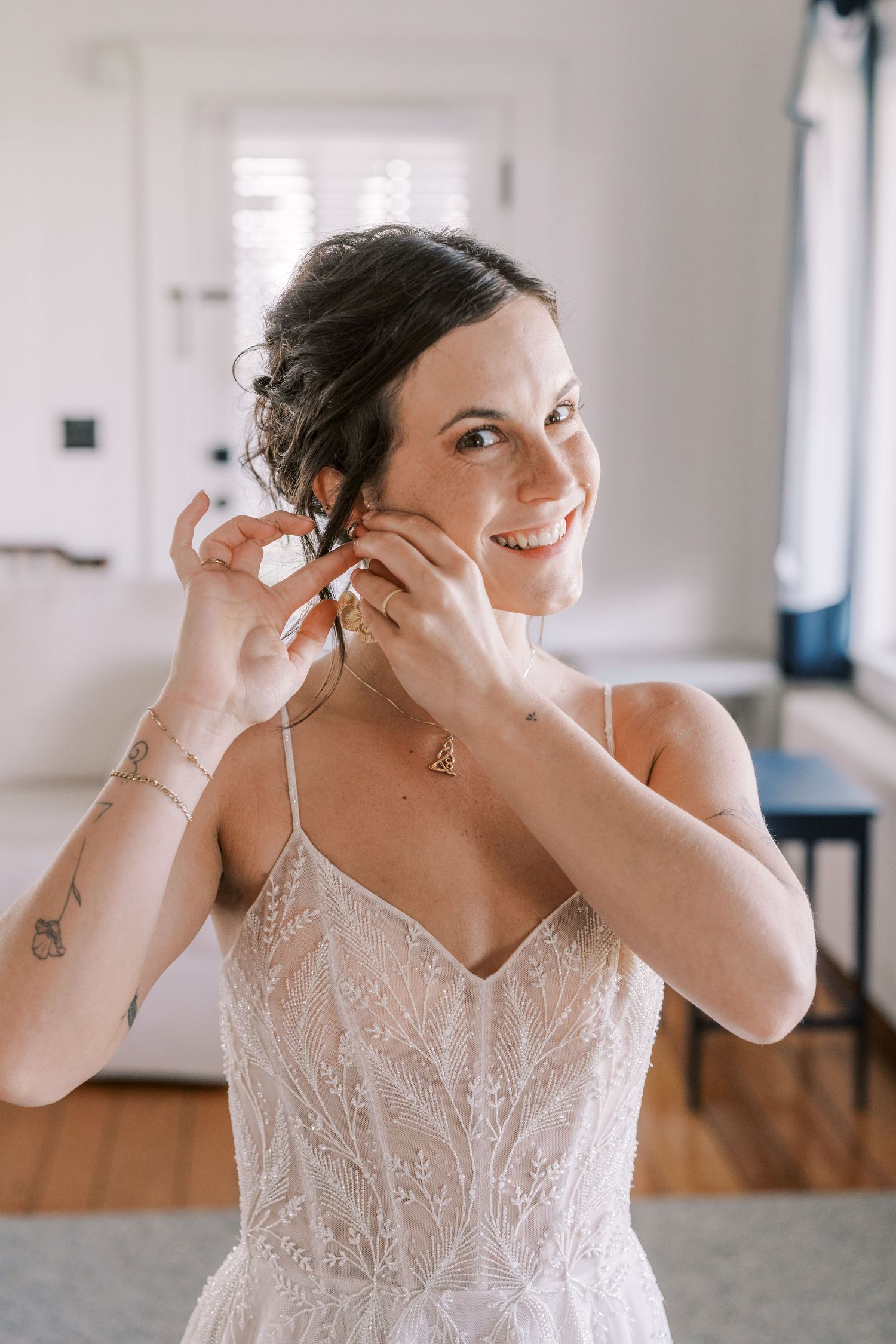 Getting ready sequence showing bride putting on jewelry in white lace dress.