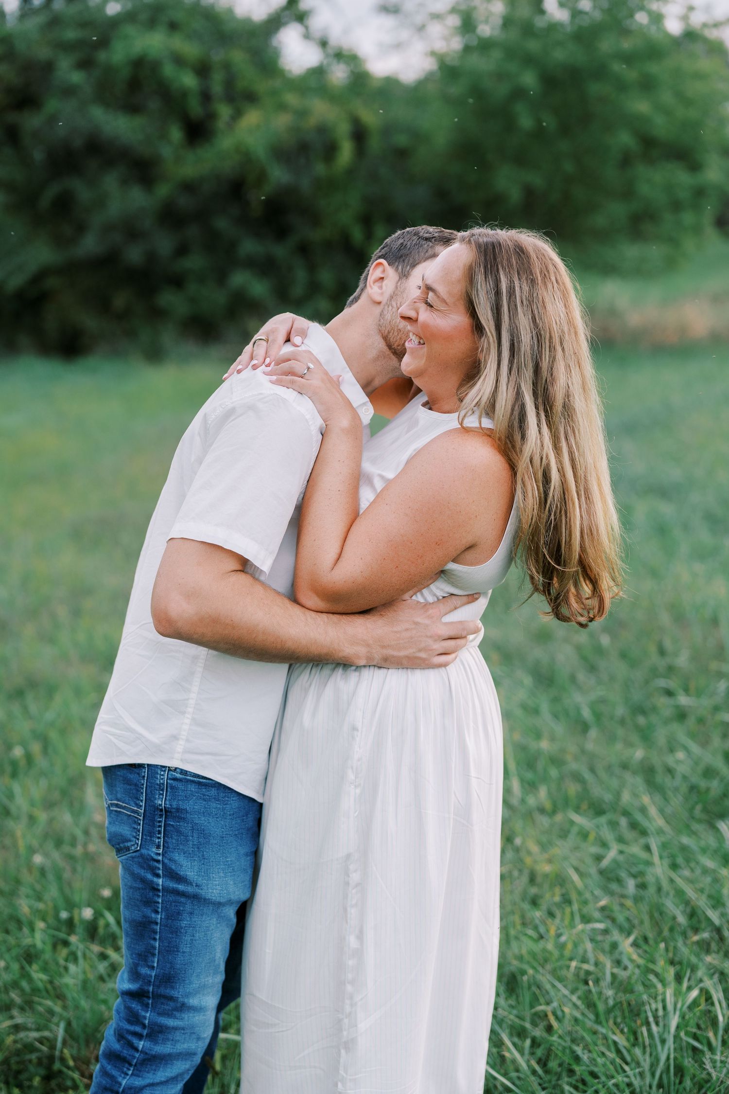 A couple sharing an intimate moment together in a lush green meadow.