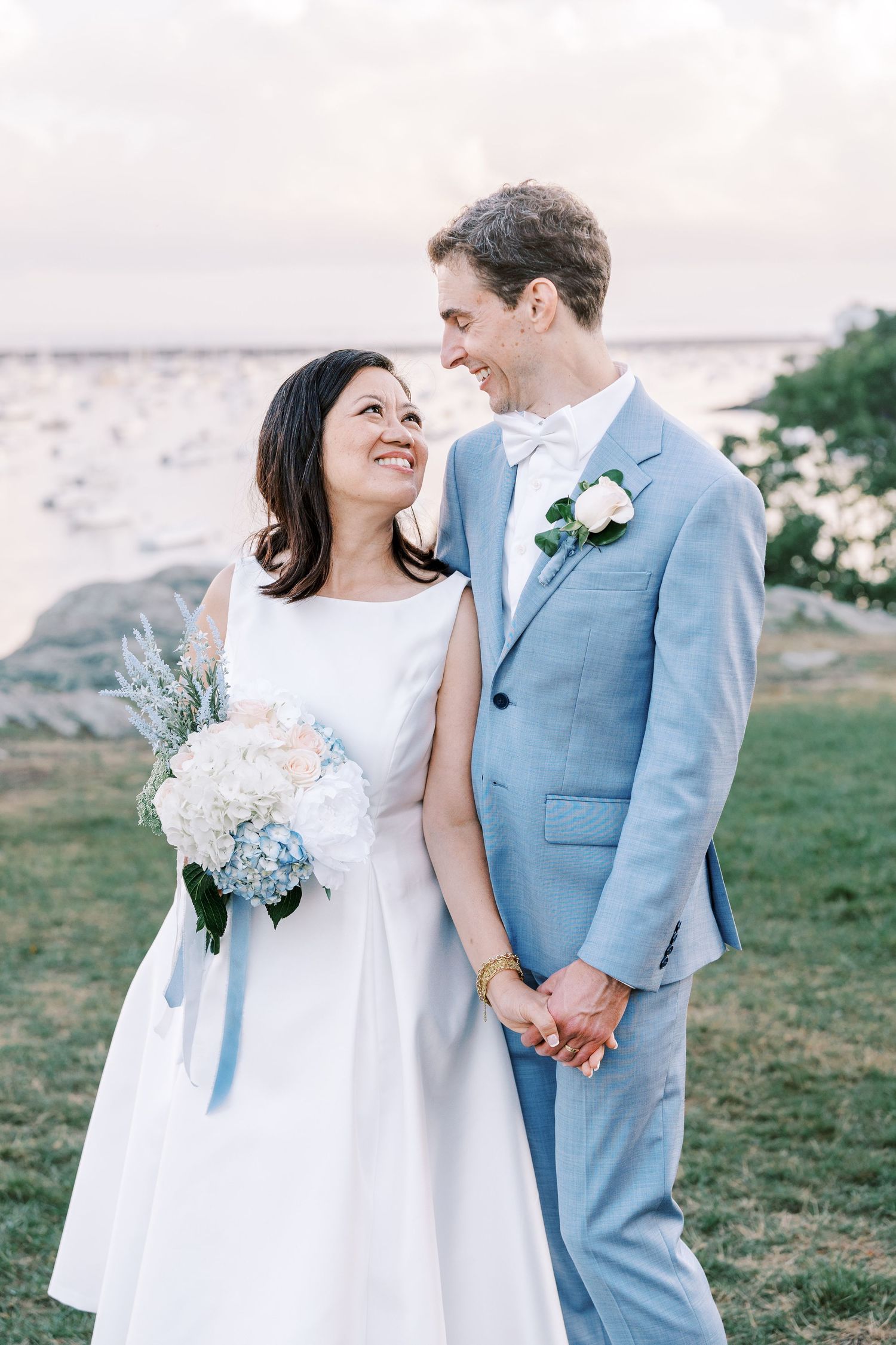 A romantic wedding couple shares a joyful moment together against a scenic outdoor background.
