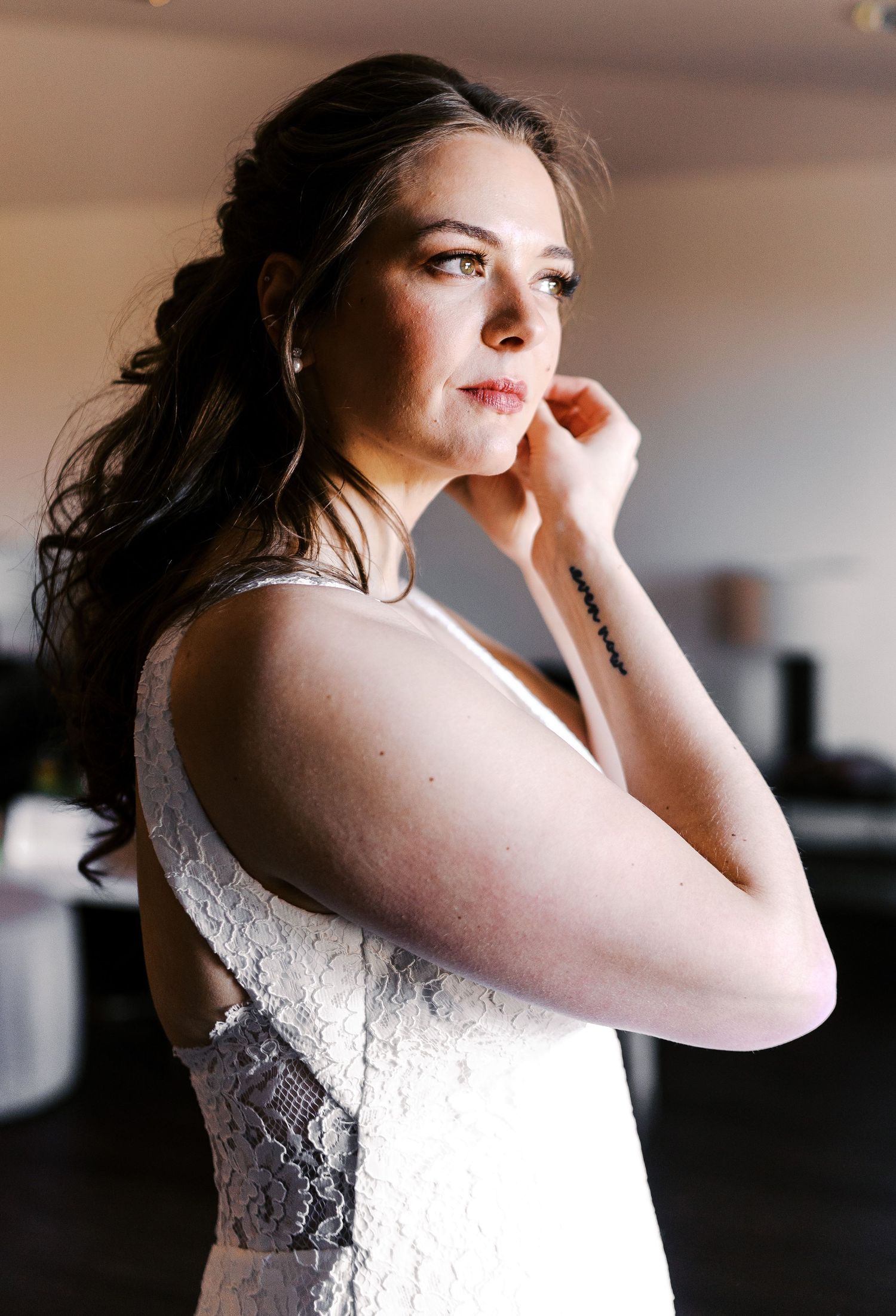 Ethereal bridal portraits in a lace white dress captured in dramatic window light.