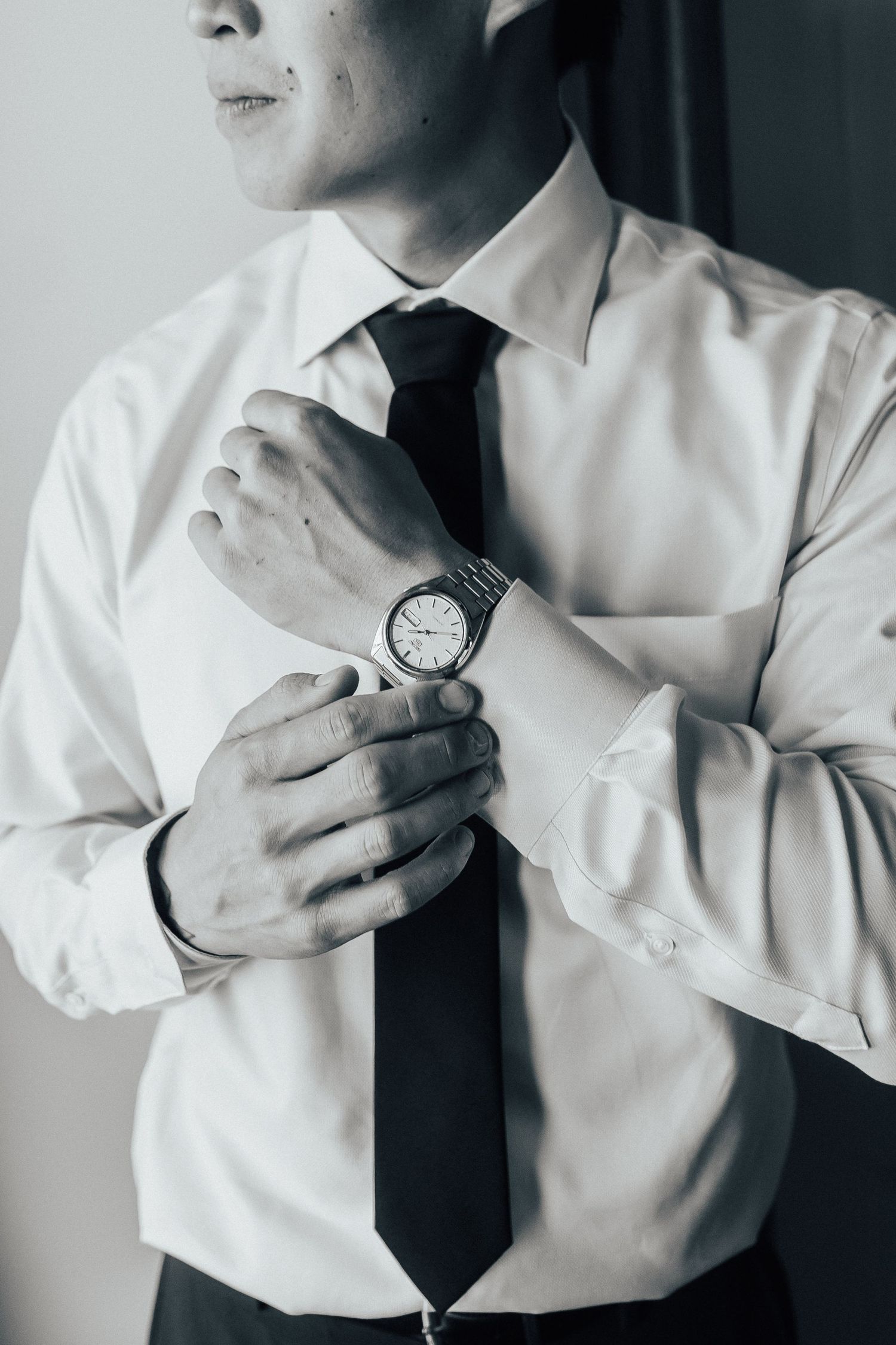 Close-up sequence of adjusting white dress shirt and tie with watch detail.