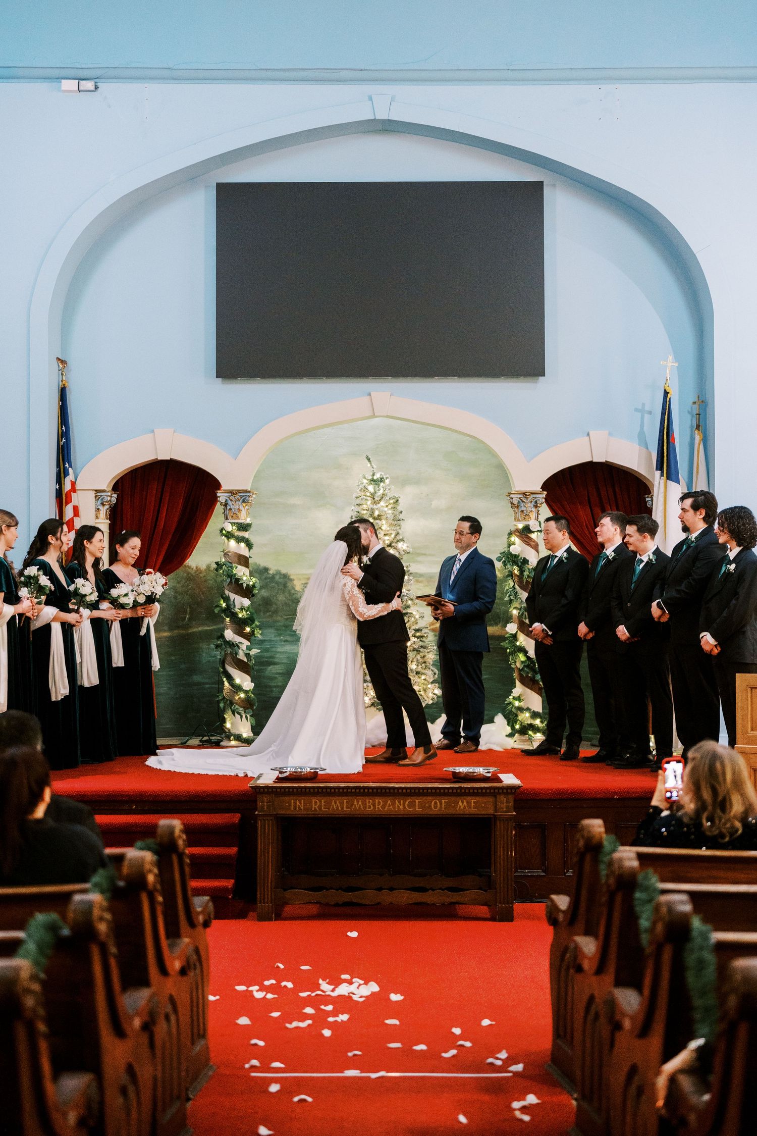 A wedding ceremony progression shown in five sequential photos of a church altar with white rose petals on red carpet.