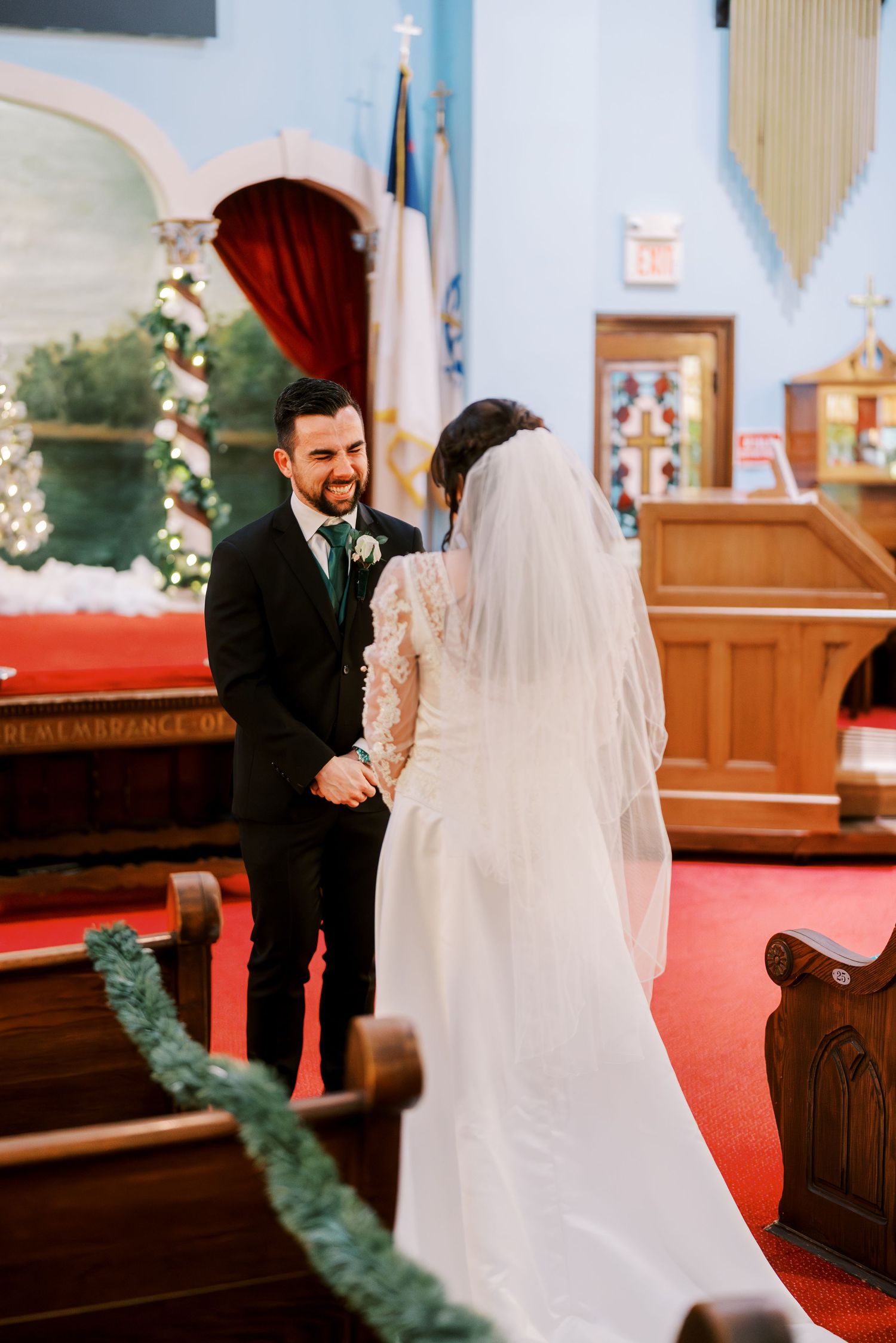 Wedding ceremony in traditional church with red carpet and floral arch decorations.