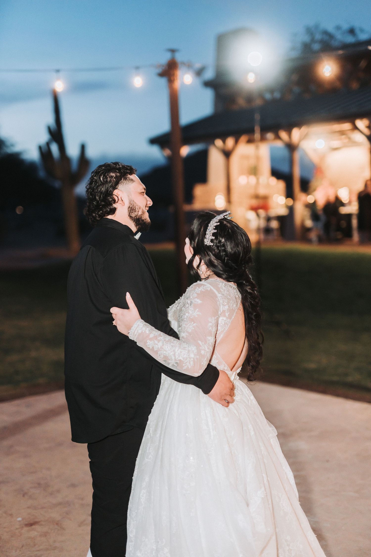 A couple shares a romantic evening dance outdoors with glowing lights and a dreamy atmosphere.