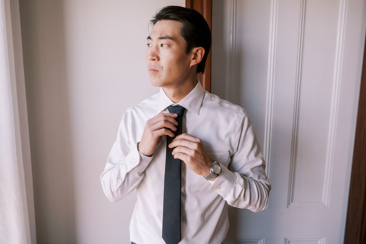 Getting ready scene showing formal attire and tie adjustments.