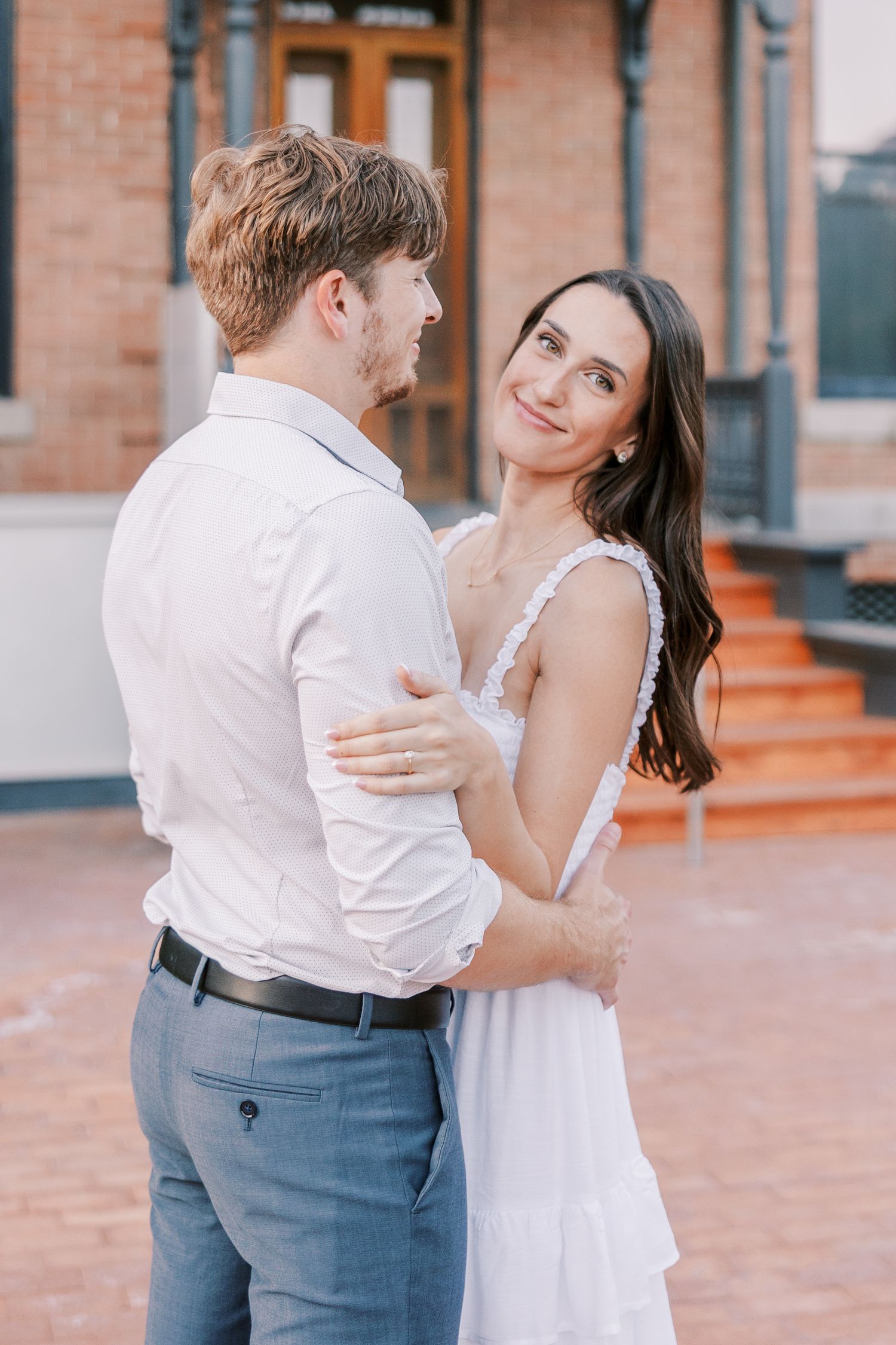 Couple dancing together on a brick patio with warm lighting in formal attire.