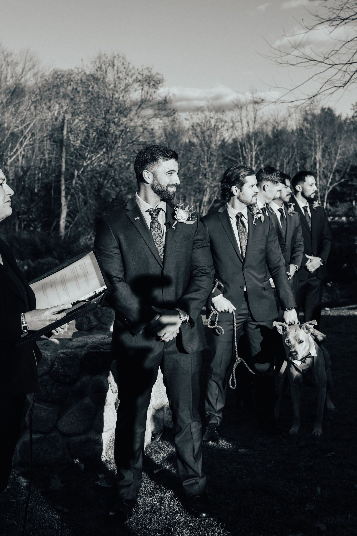 Black and white photo series showing groomsmen in suits striking silly running poses outdoors during a wedding photoshoot.
