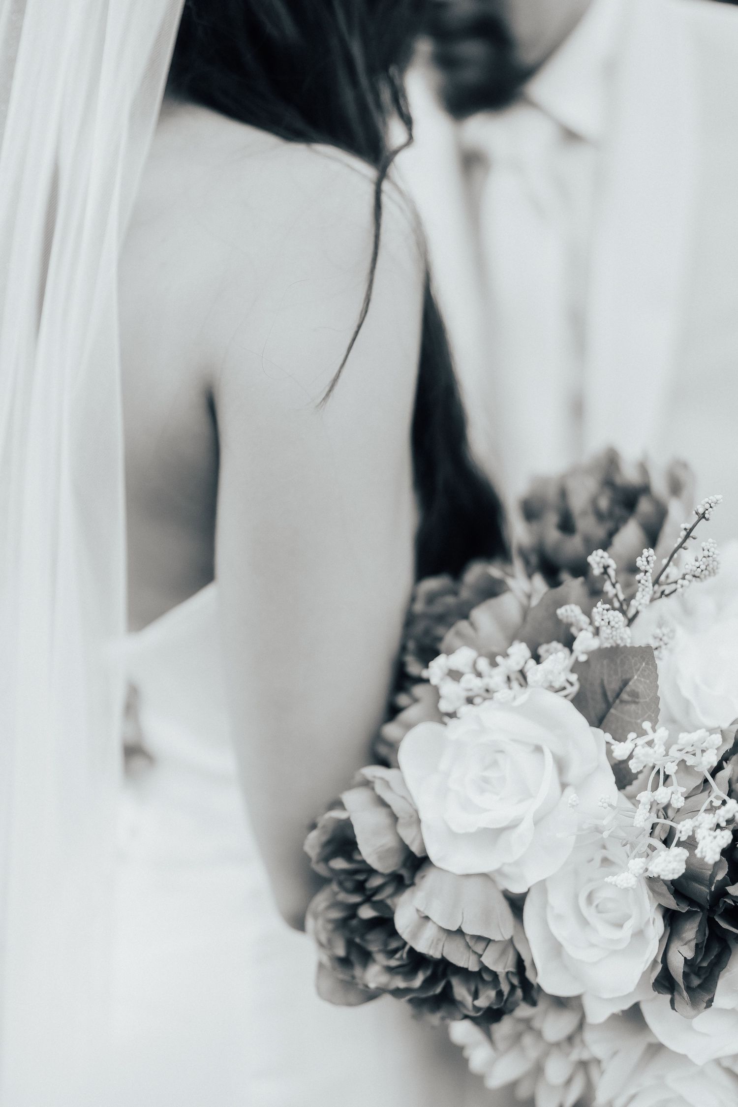 Elegant white roses and delicate flowers create a romantic bridal bouquet arrangement against a soft white background.