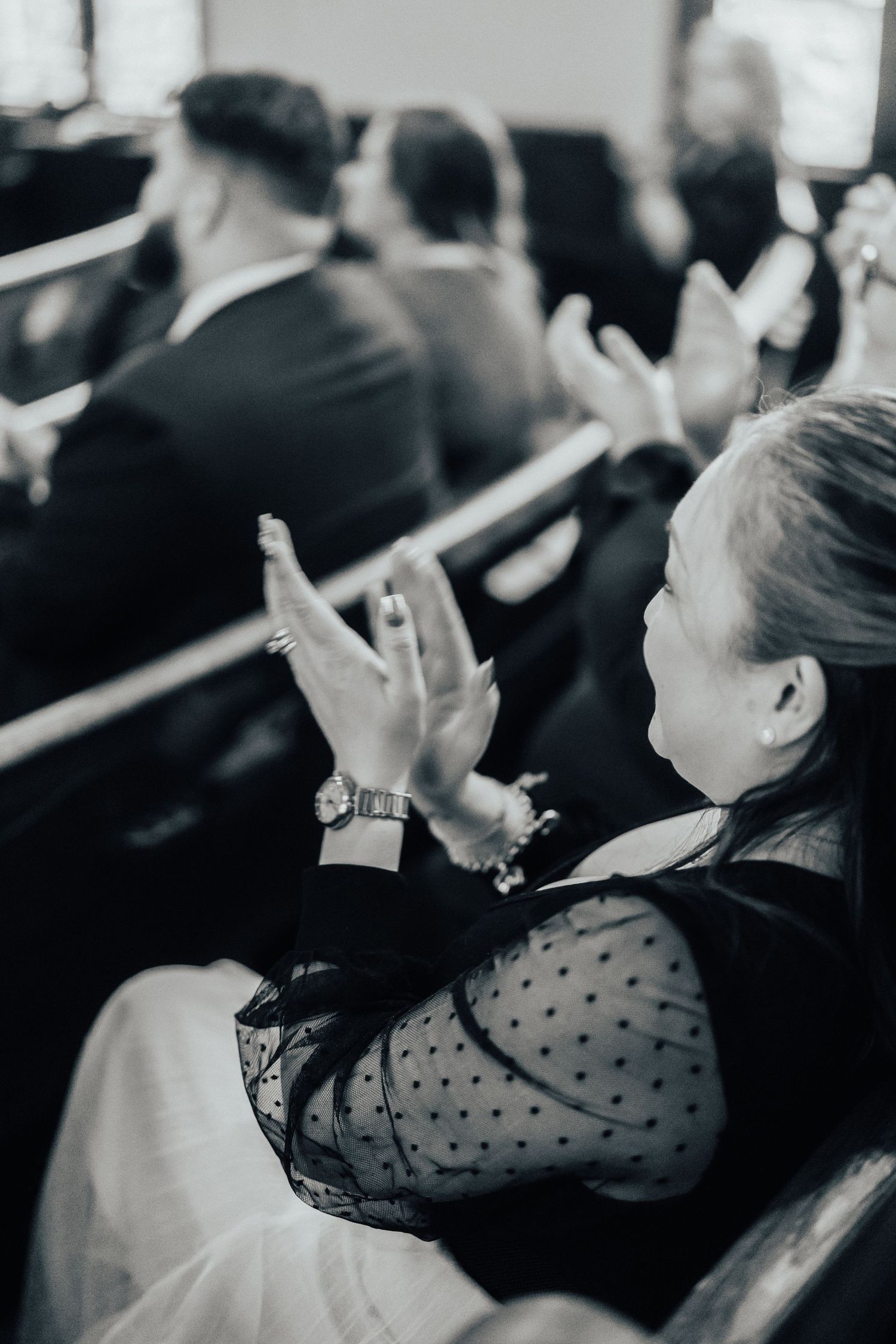 Black and white photo of wedding guests clapping during ceremony.
