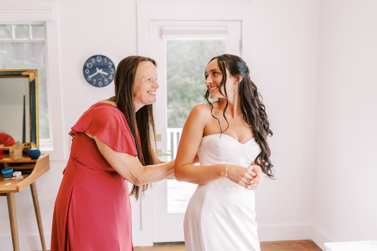 Emotional candid moment captured in a bright white room with natural light streaming through windows.