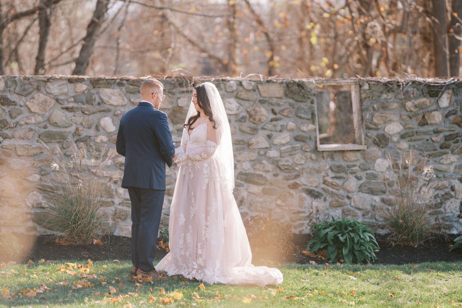 A romantic couple shares tender moments against a rustic stone wall backdrop during an outdoor wedding photoshoot.