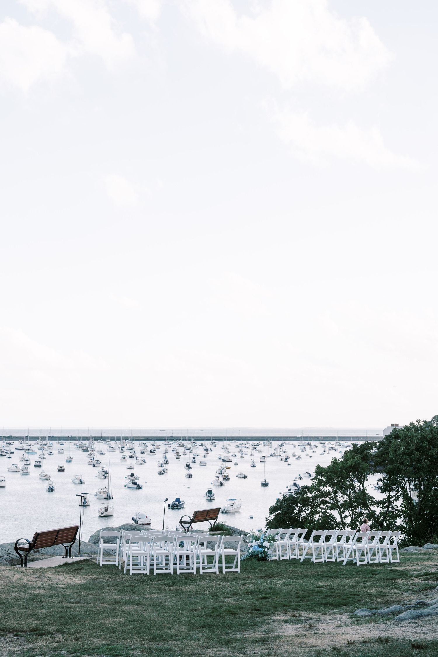 White chairs arranged in rows for an outdoor waterfront ceremony with boats in the background.