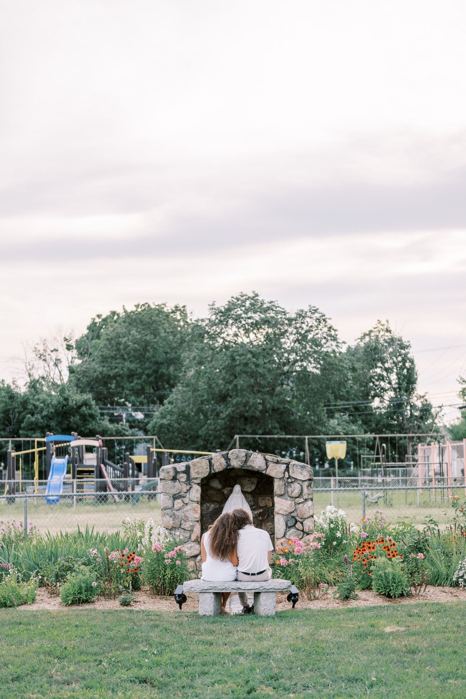 A scenic garden landscape with stone walls and flowering plants at sunset.