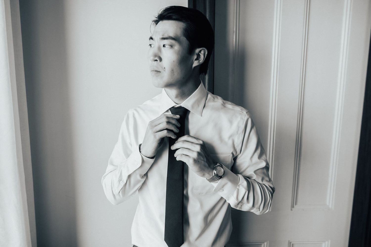 Black and white portrait series showing a person adjusting their tie and getting ready.