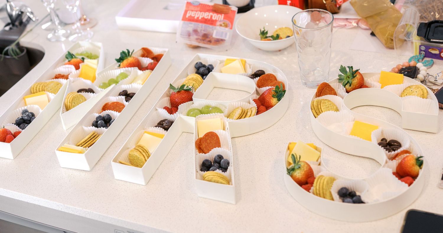 Various fresh fruit and berry platters arranged neatly on white serving trays at a catering event.