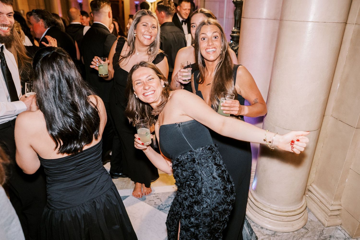 Celebration on a dance floor with guests in formal attire dancing and mingling at an upscale venue.