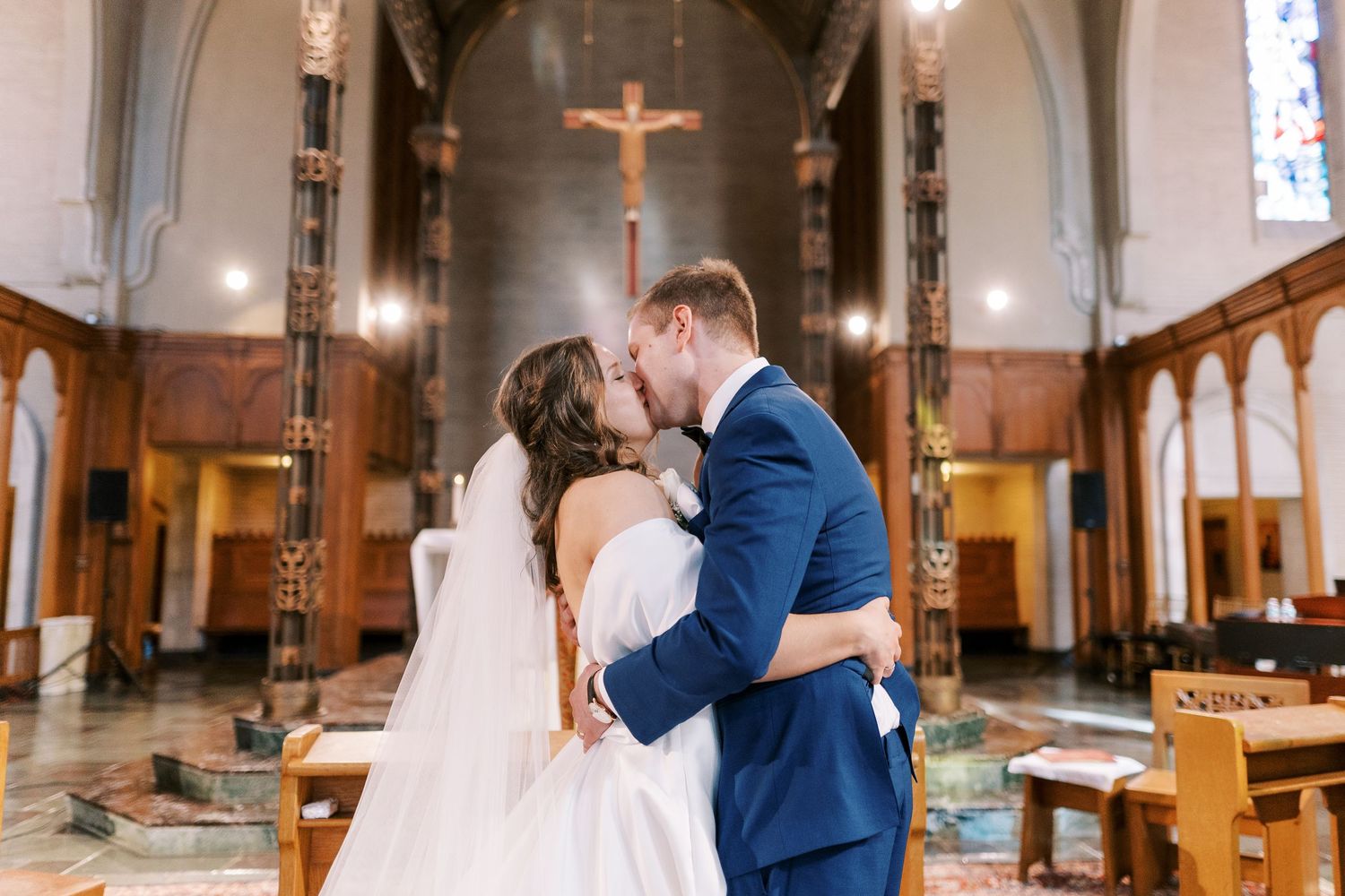 Romantic moment captured inside a traditional church with stained glass windows and wooden pews.