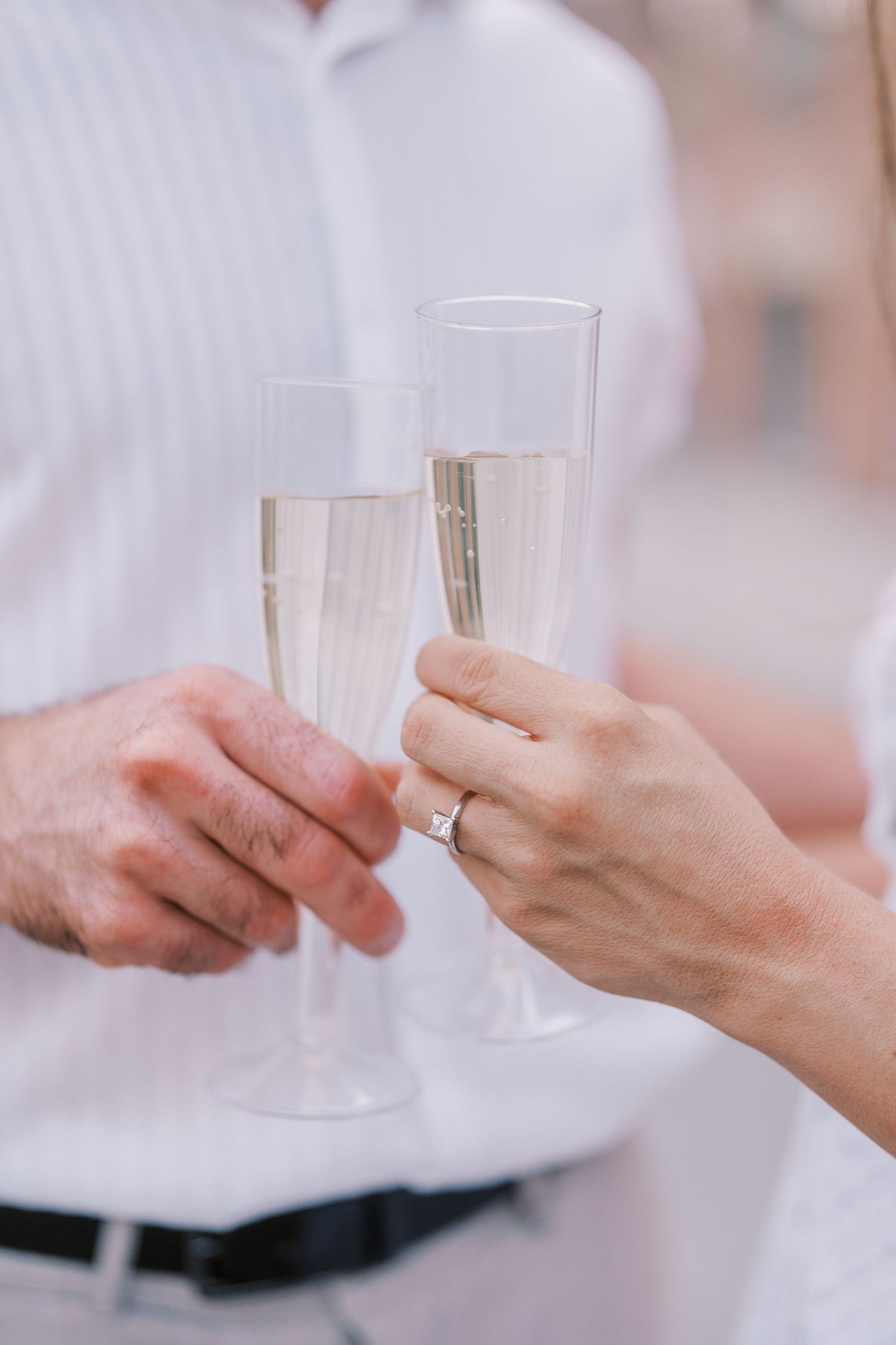 Close-up view of hands exchanging champagne glasses in a celebratory toast.