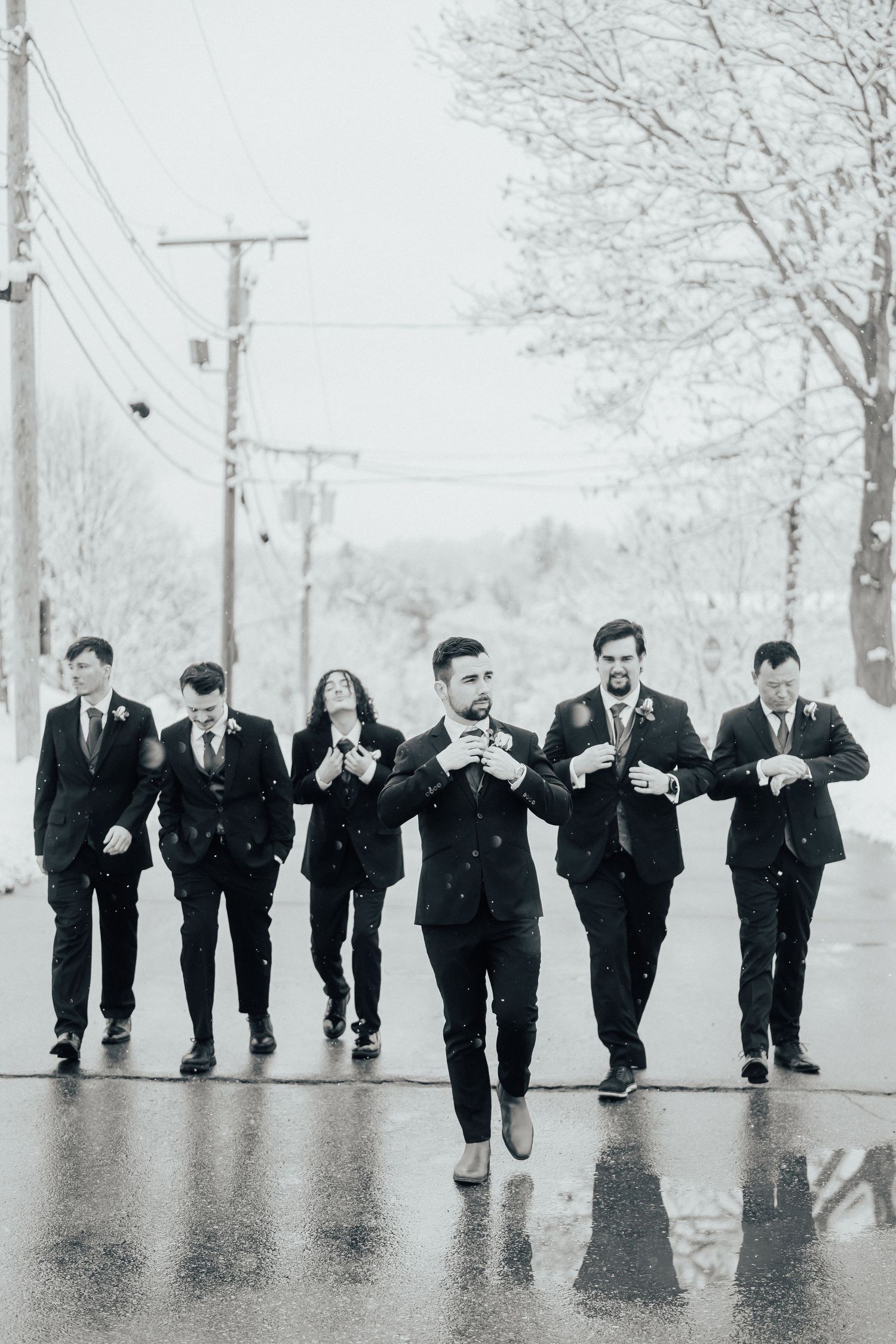 A group walks down a rainy street in formal attire during winter.