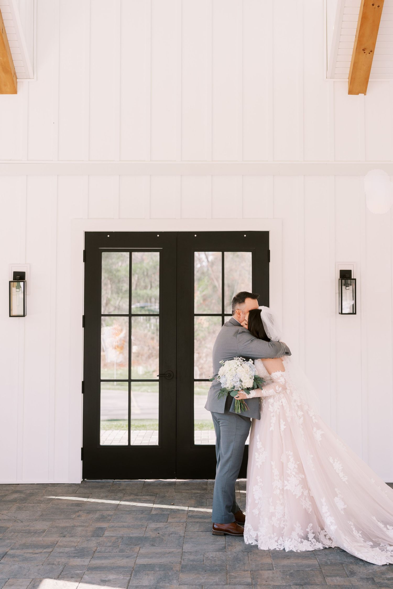 A romantic first look moment between a couple at a venue with white walls and black French doors.