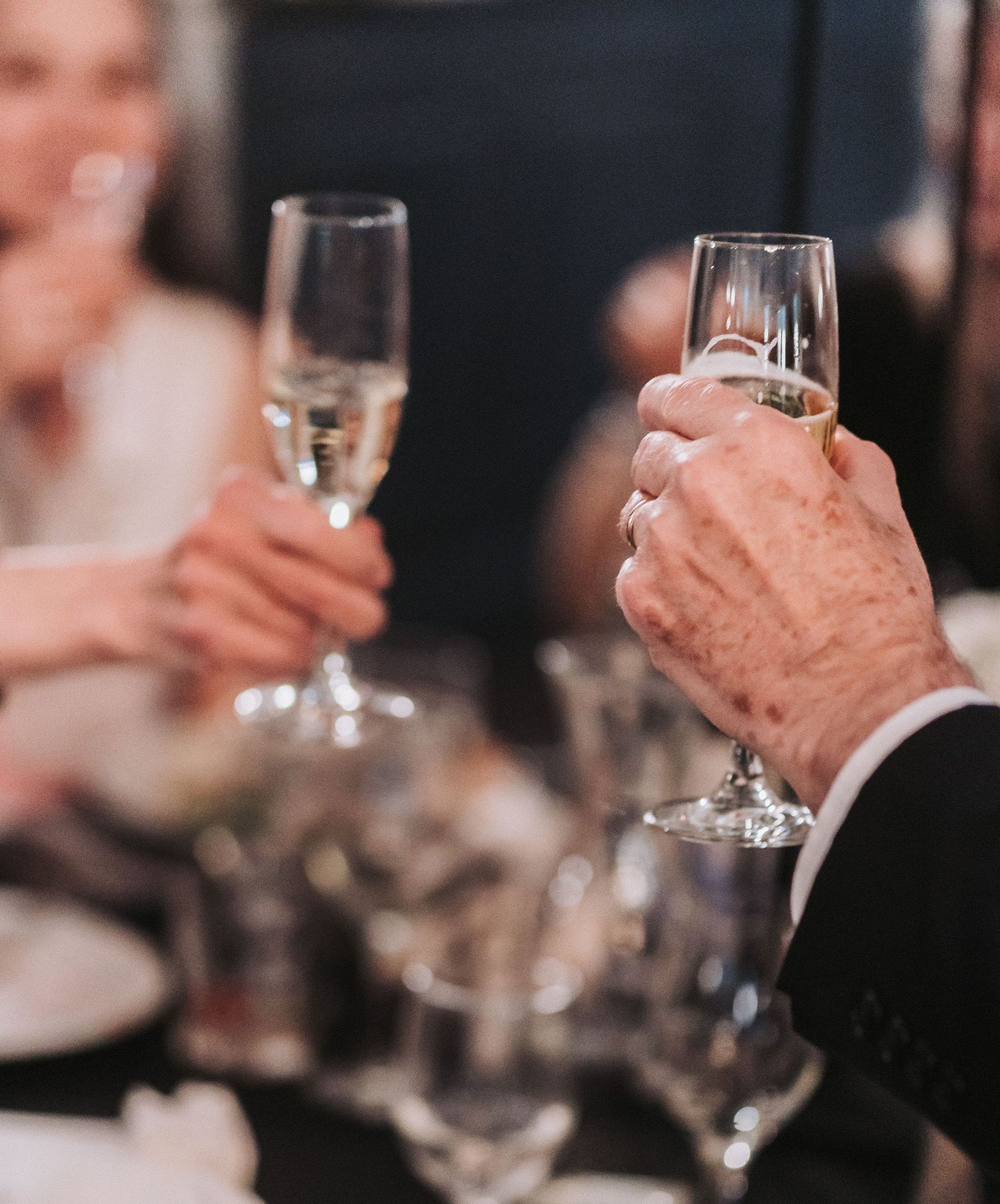 Close-up of hands holding champagne glasses during a wedding toast celebration.