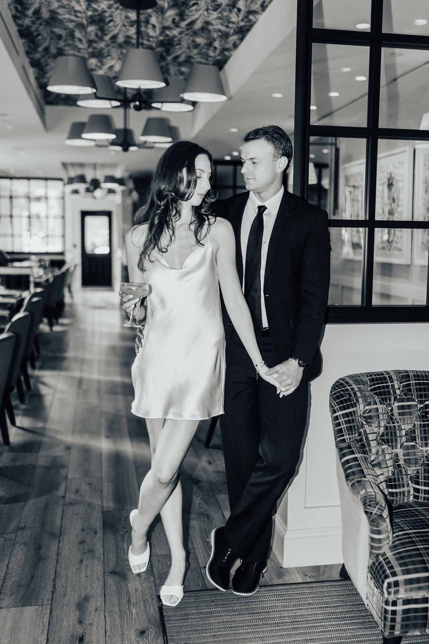 Black and white photo of a wedding couple in an elegant indoor venue with hardwood floors and modern lighting.