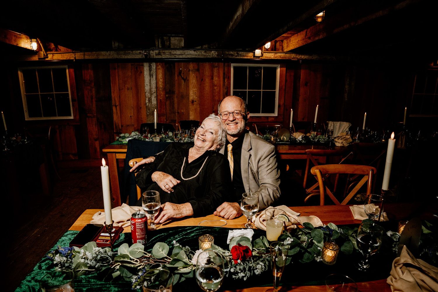 Romantic couple shares intimate moment at candlelit dinner table with wine glasses and cozy ambiance.