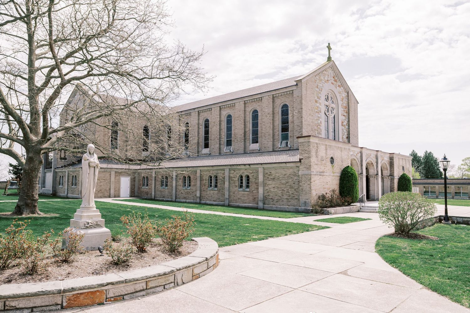 Stone church exterior with Gothic architecture and landscaped grounds on an overcast day.