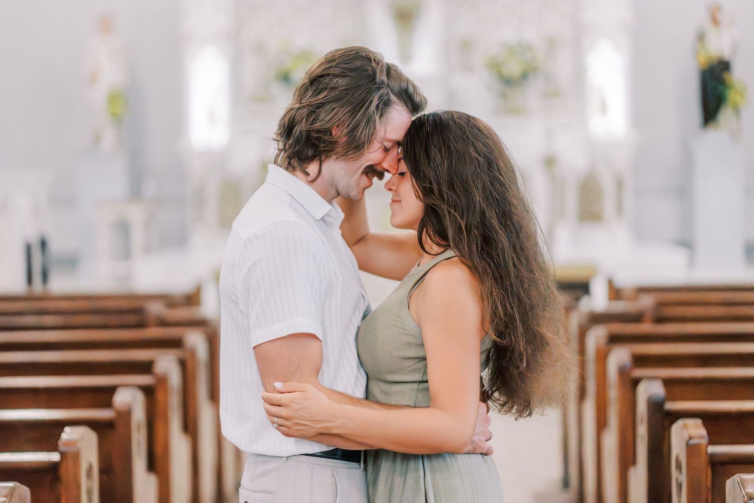 A romantic couple sharing an intimate moment in an ornate church with wooden pews.