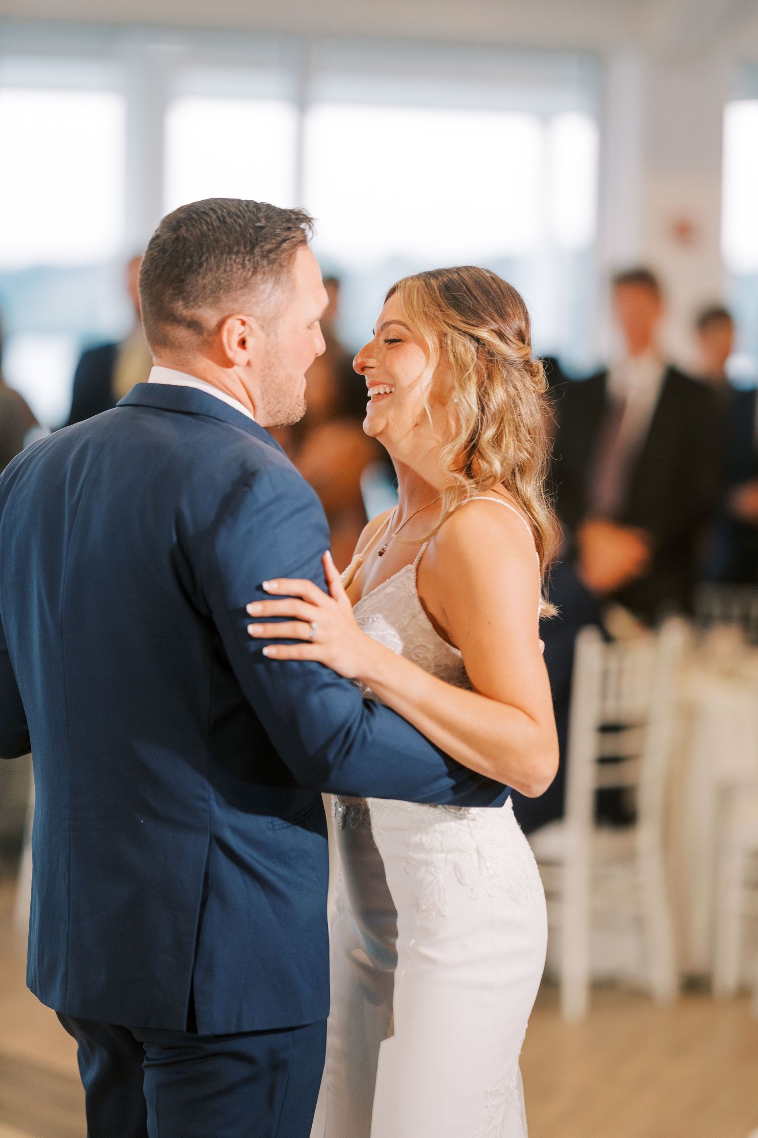 A couple shares an intimate dance together at their wedding reception in a bright, airy venue.