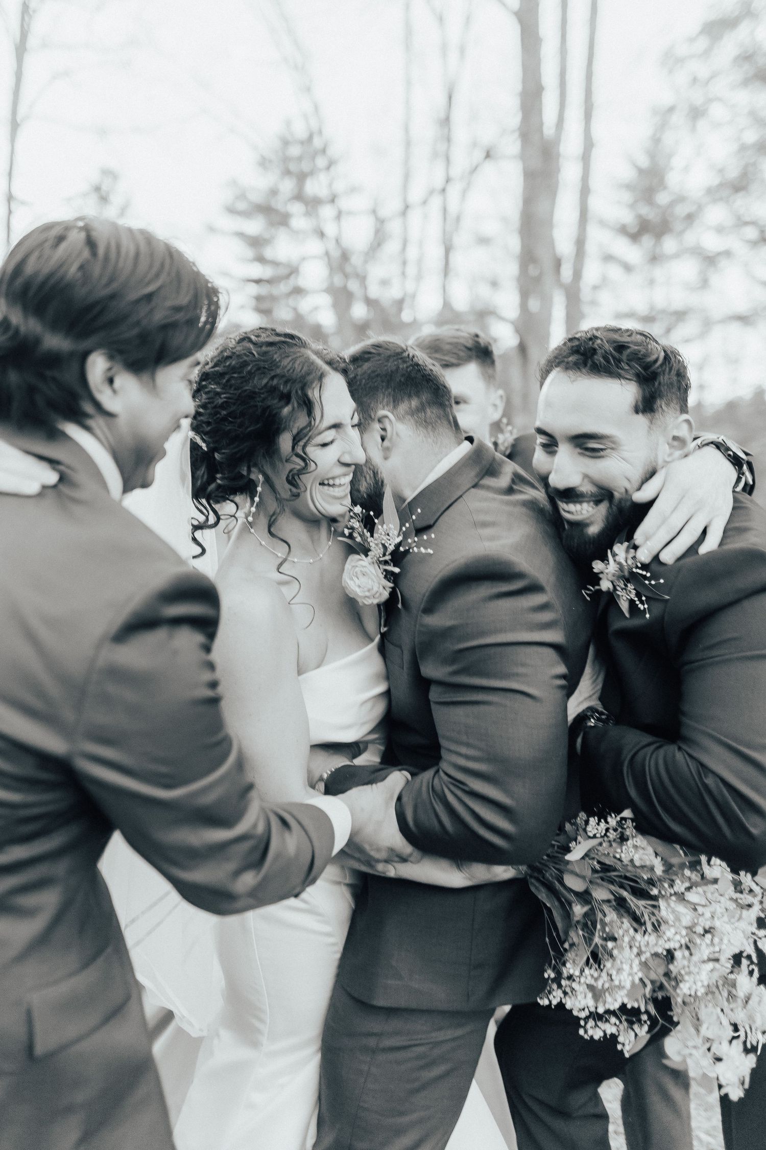 A group embraces in a candid black and white photo sequence showing joyful emotion at an outdoor celebration.