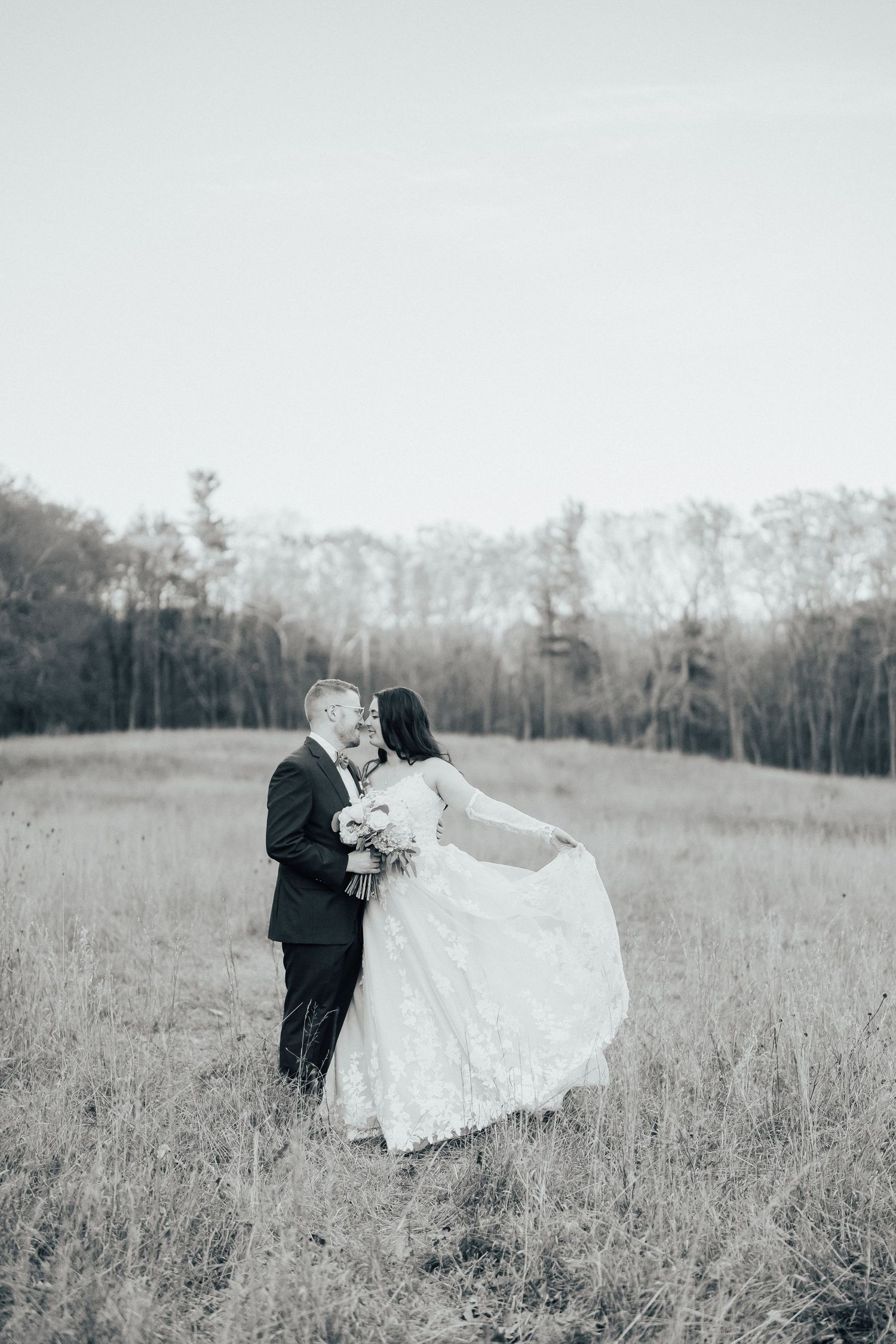 Black and white wedding photos show a couple dancing and embracing in a rustic field with trees in the background.