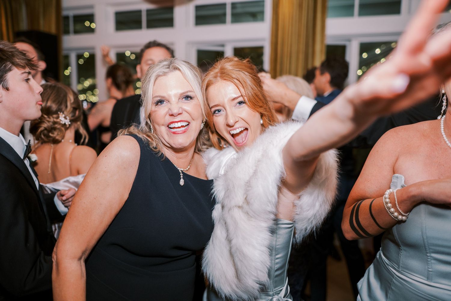 Wedding guests dancing and celebrating enthusiastically on a lively dance floor during a reception.
