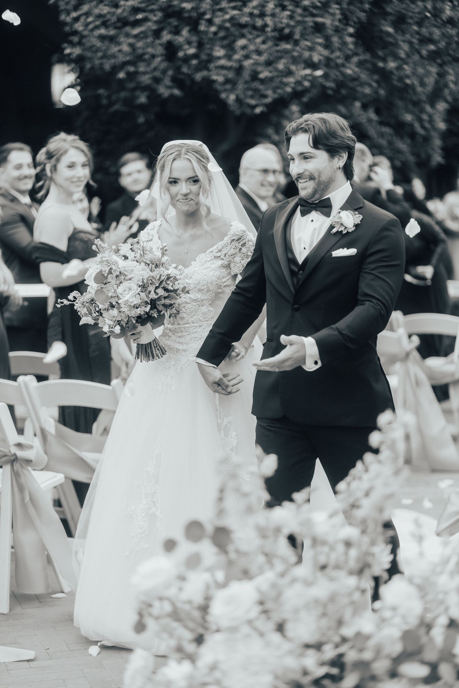 A romantic outdoor wedding ceremony features guests celebrating as confetti falls through the air during a joyous moment.
