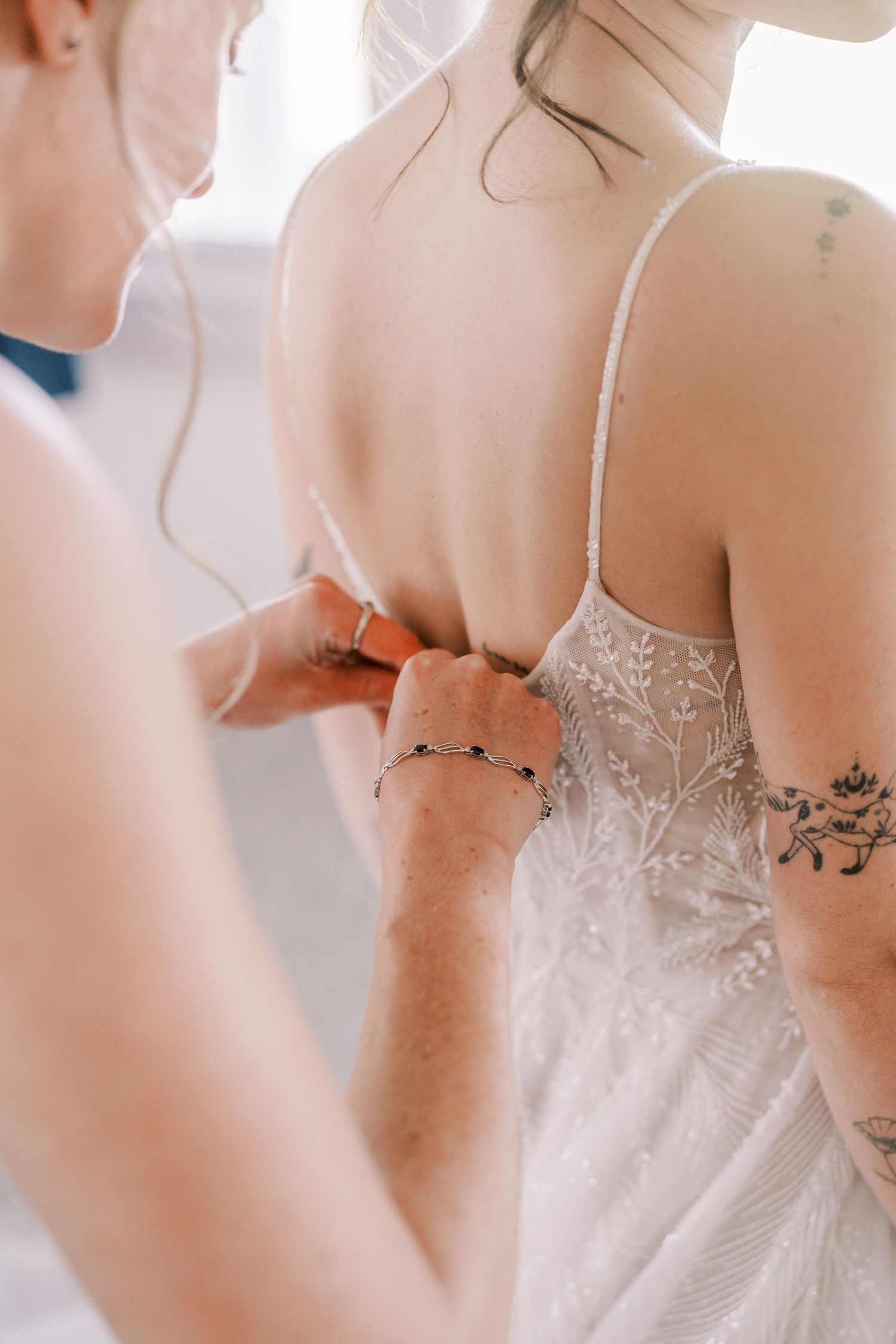 Close-up detail of intricate lace and beading on the back of a white wedding dress.