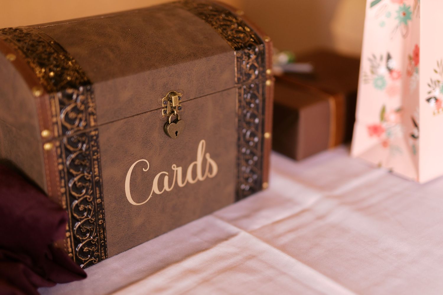 A vintage-style brown wooden card box with gold lettering and decorative metal trim sits on a white tablecloth.